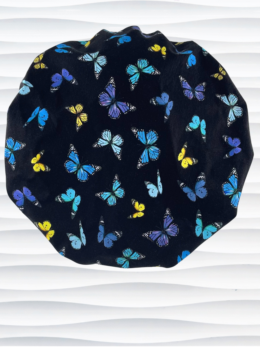 Bouffant style surgical scrub cap hat with blue, purple, and yellow butterflies all over black cotton fabric.