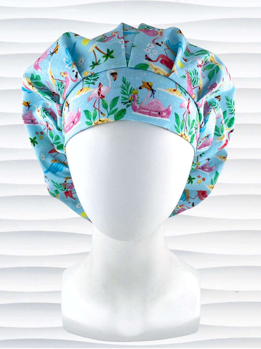Bouffant style surgical scrub cap hat with cute flamingos, tropical flowers, island drinks, and surf waves on light blue cotton fabric.