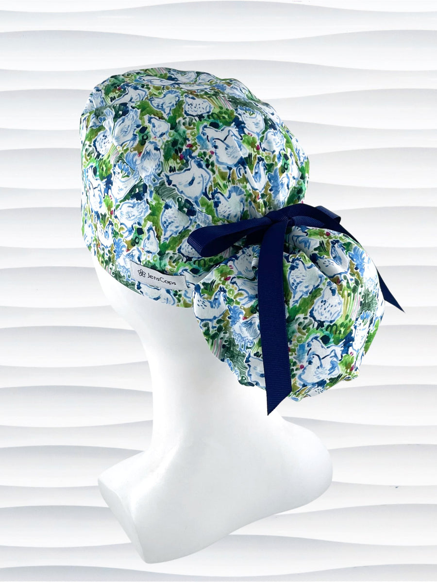 Ponytail style surgical scrub cap hat with a digital print of white chickens with flowers in blues and greens on white cotton fabric.