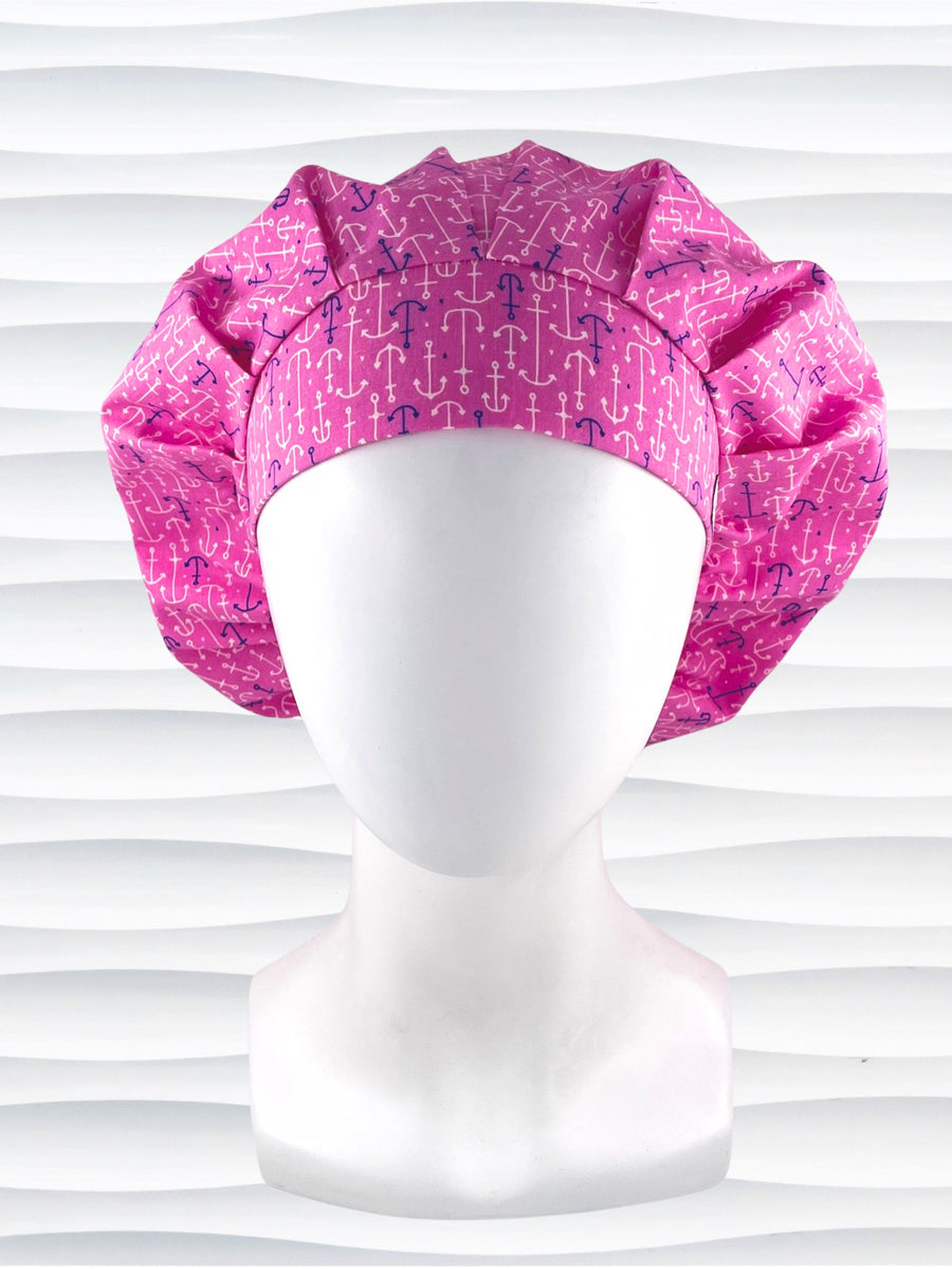 Bouffant style surgical scrub cap hat with purple and white anchors all over this pink cotton fabric