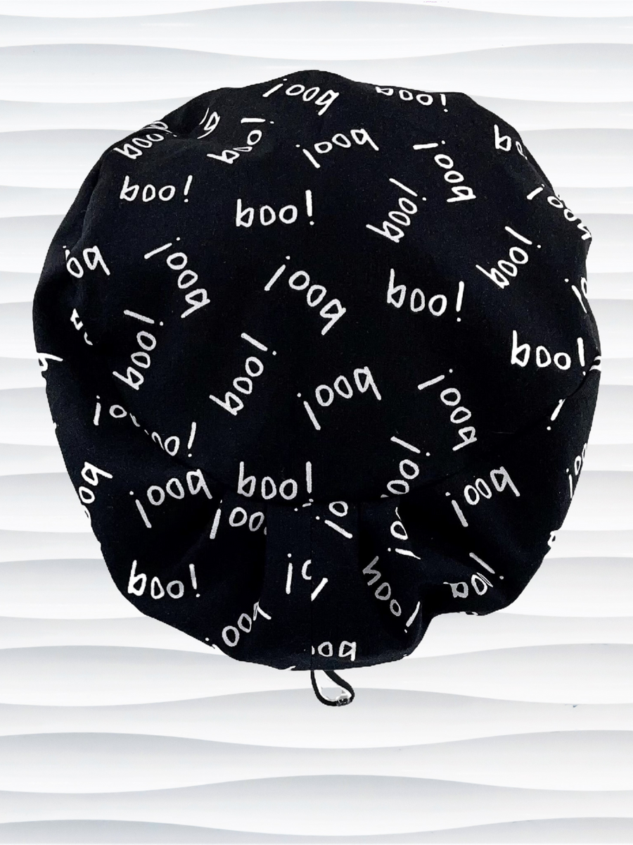 Pixie Euro style surgical scrub cap hat with the word boo in white print tossed all over this black fabric.