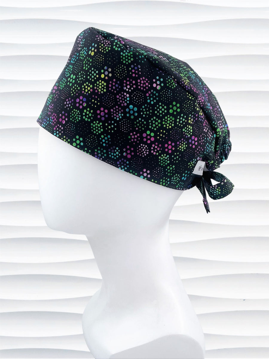 Unisex style surgical scrub cap hat with floral hexagons in purple and greens on black cotton fabric.
