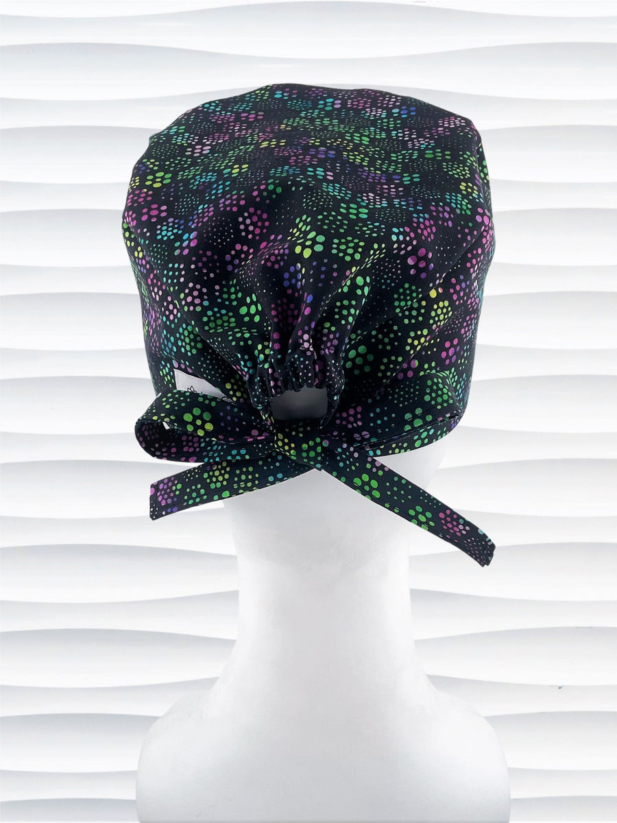 Unisex style surgical scrub cap hat with floral hexagons in purple and greens on black cotton fabric.