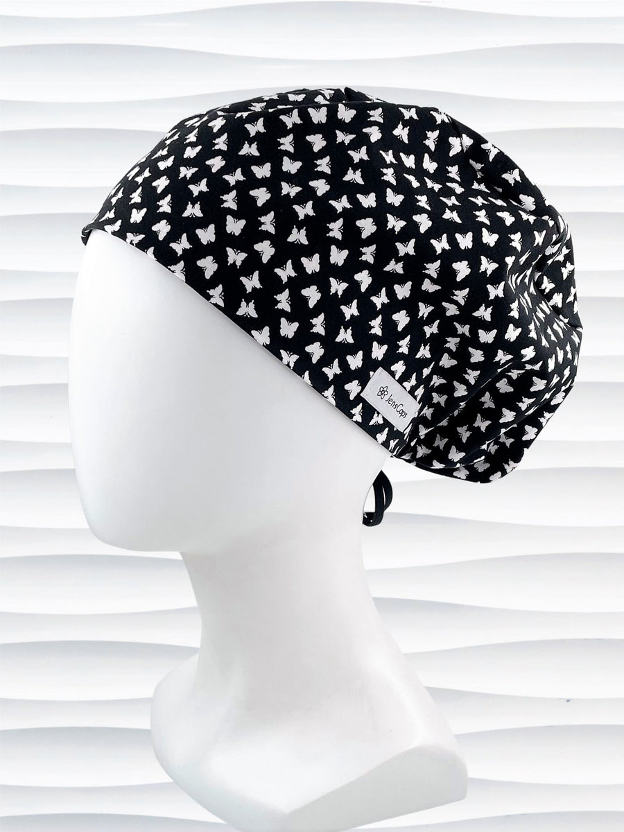 Pixie Euro style scrub cap with white butterflies on black cotton fabric.