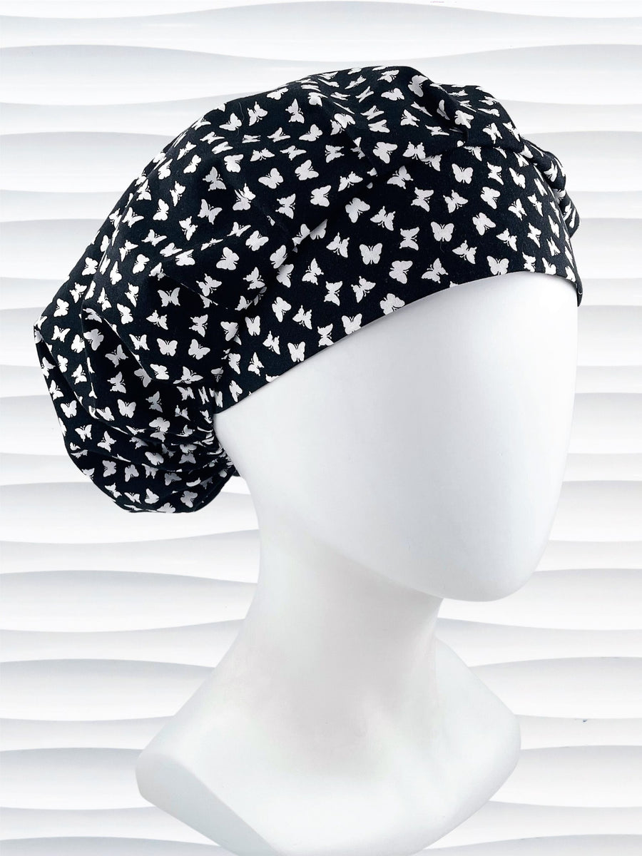 Original Bouffant style scrub cap hat with white butterflies on black cotton fabric.