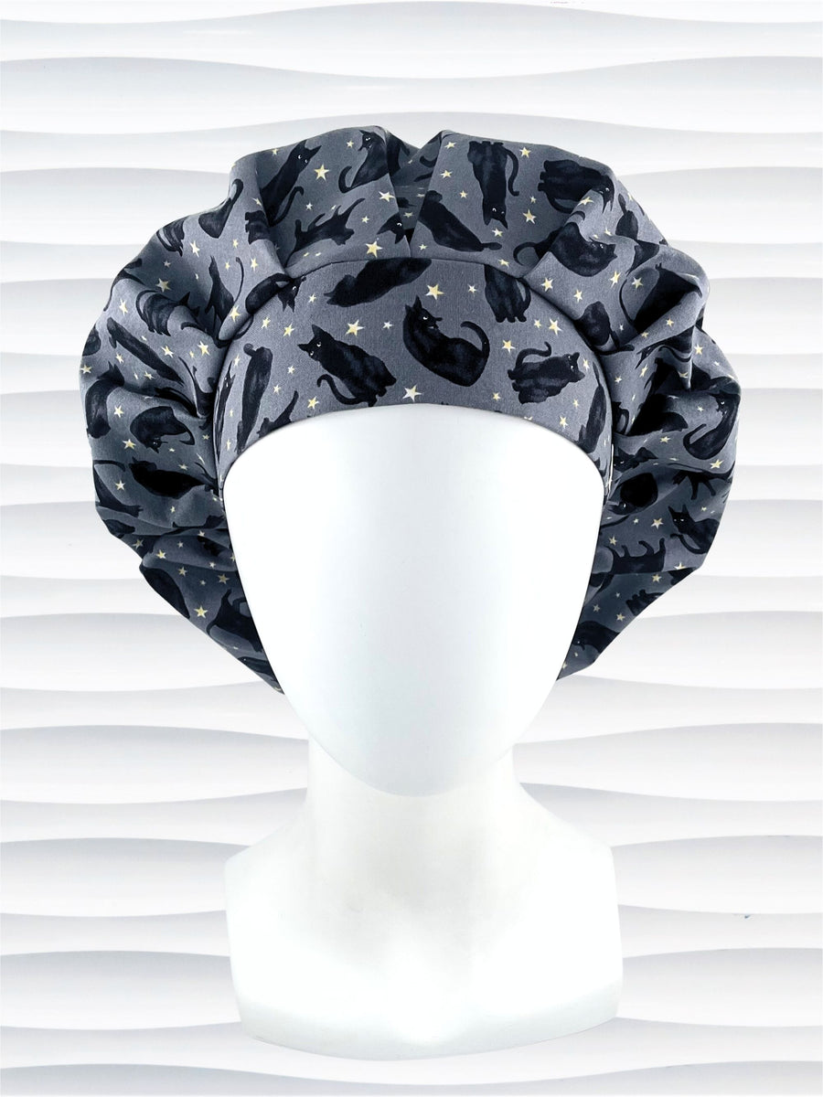 Bouffant style surgical scrub cap hat with black cats and yellow and white stars on a dark gray premium cotton fabric.