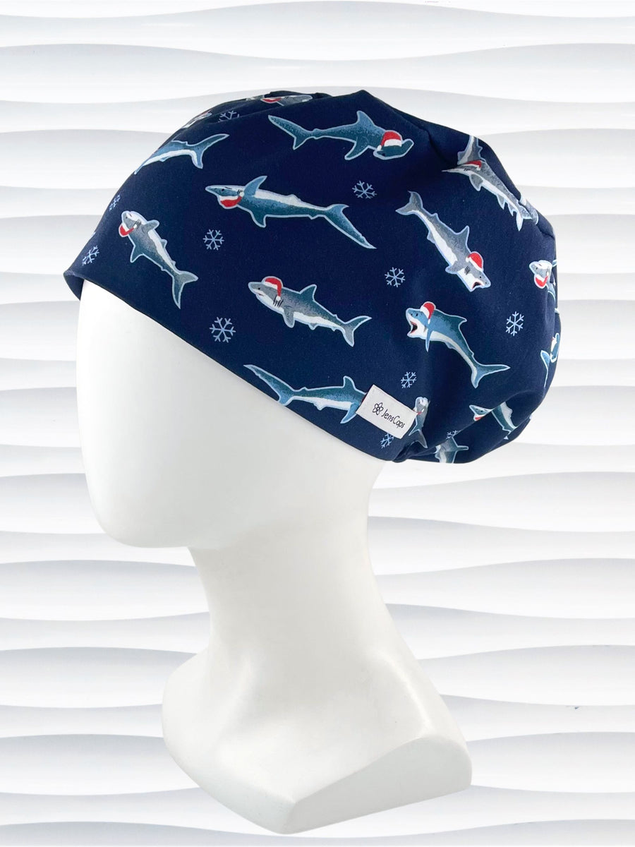 Pixie euro style surgical scrub cap hat with snowflakes and sharks wearing Santa hats on dark blue cotton fabric.