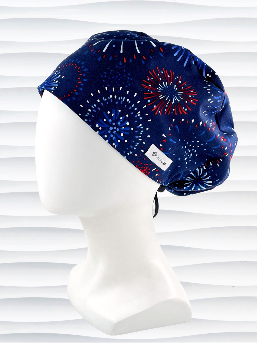 Pixie Euro style surgical scrub cap hat with red white and blue fireworks on dark blue cotton fabric.