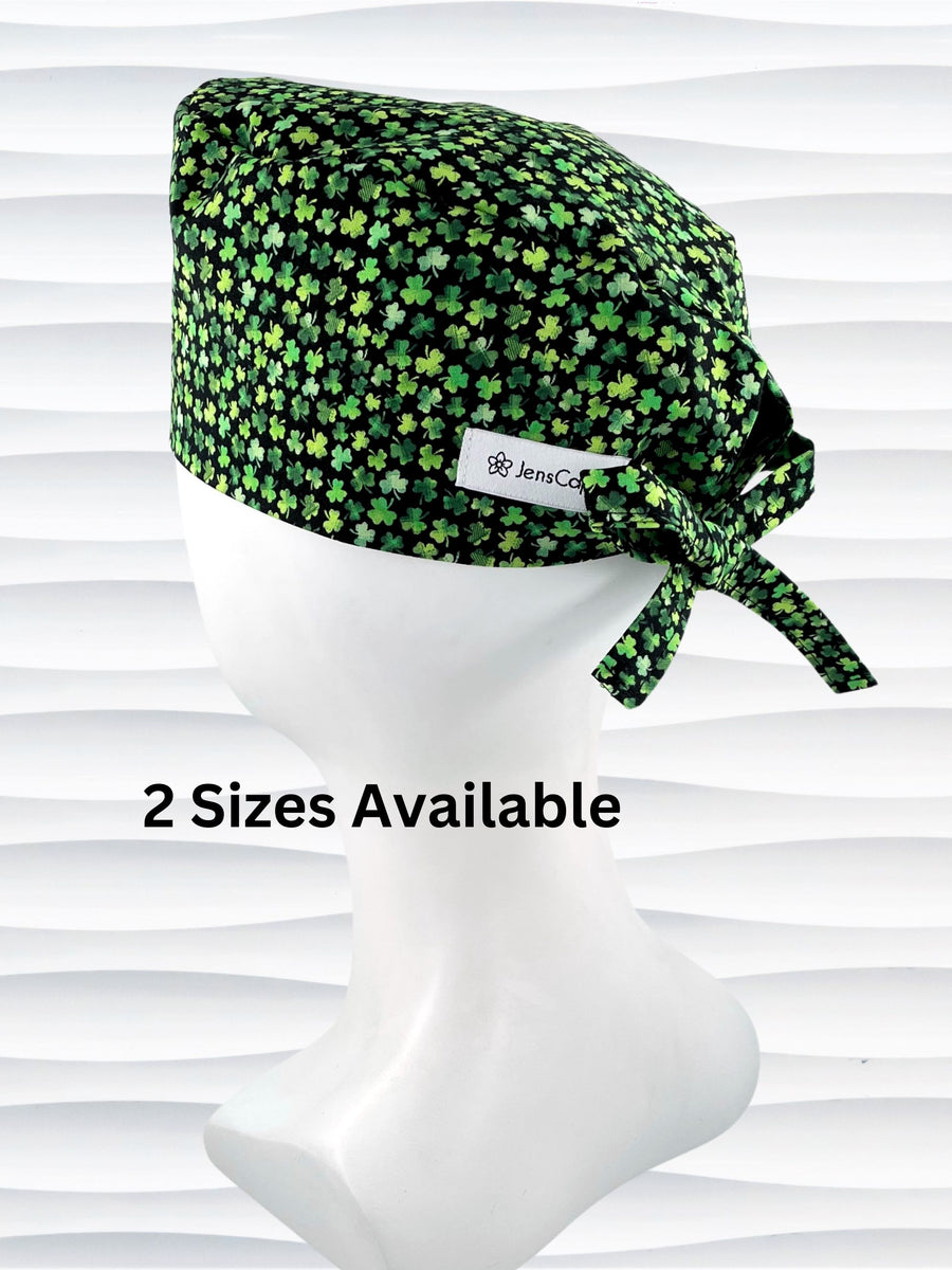 Surgeon style surgical scrub cap hat with an allover print of small green shamrocks on black cotton fabric.