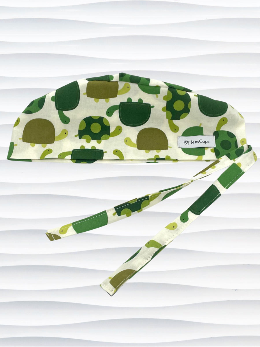 Surgeon style surgical scrub cap hat with an allover pattern of green cartoon turtles with dots on cotton fabric.