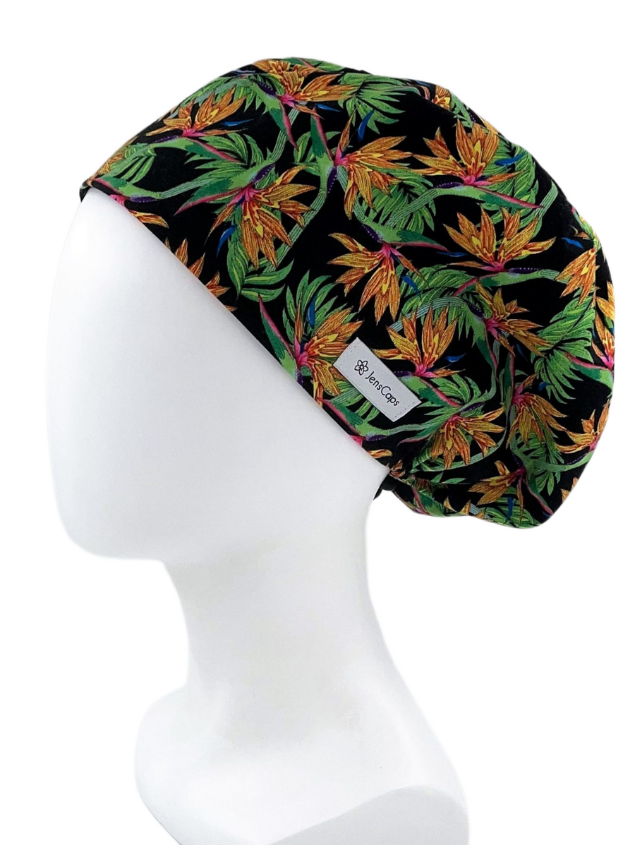 Pixie Euro style surgical scrub cap hat. This cotton fabric has an allover print of bird of paradise flowers and stems on a black background 