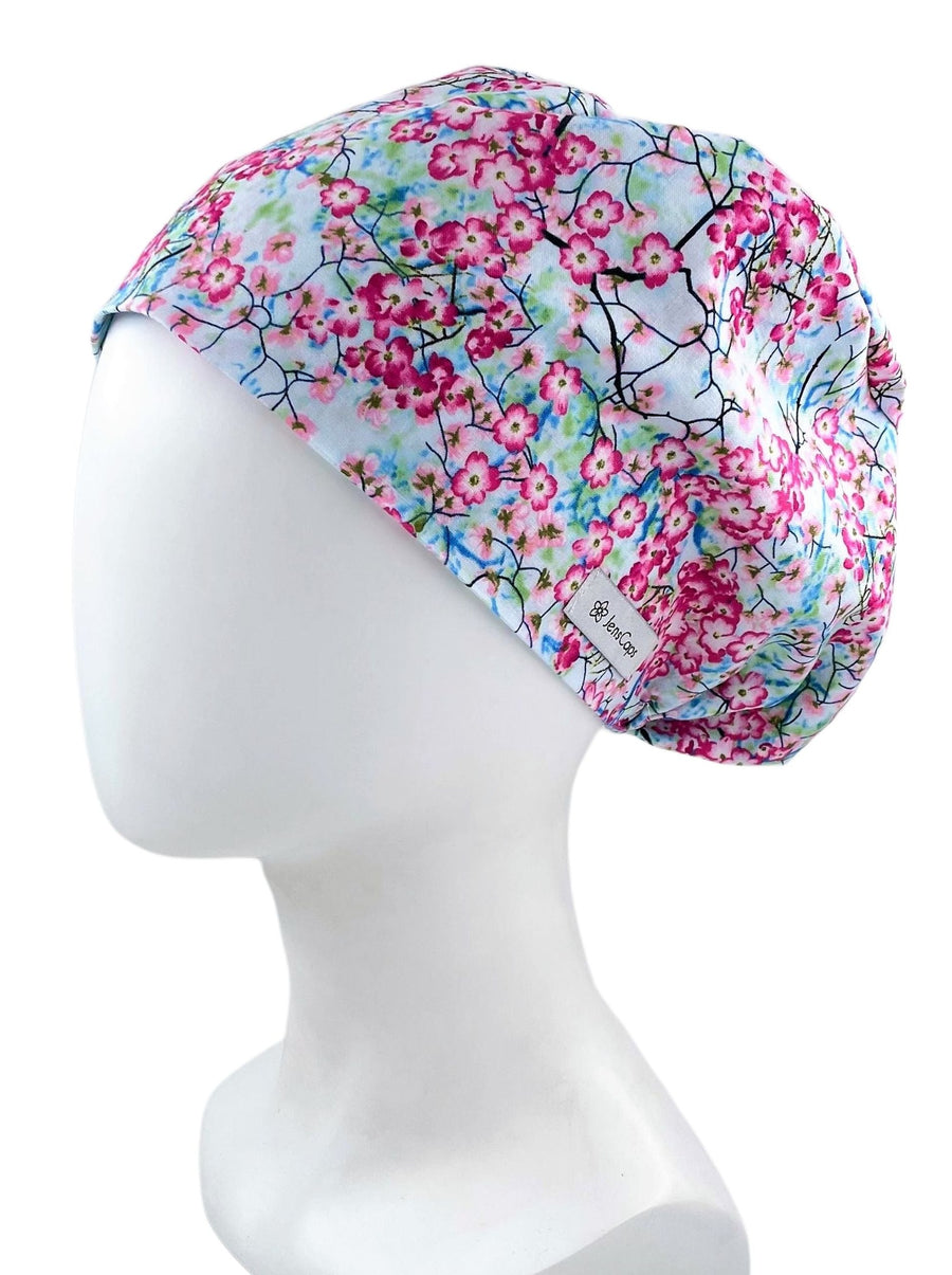 Bouffant style surgical scrub cap hat. This premium cotton fabric has cherry flower blossoms and branches on a blue sky background