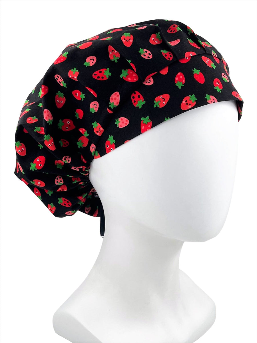 Bouffant style scrub cap with red strawberries and green stems on black premium cotton fabric.