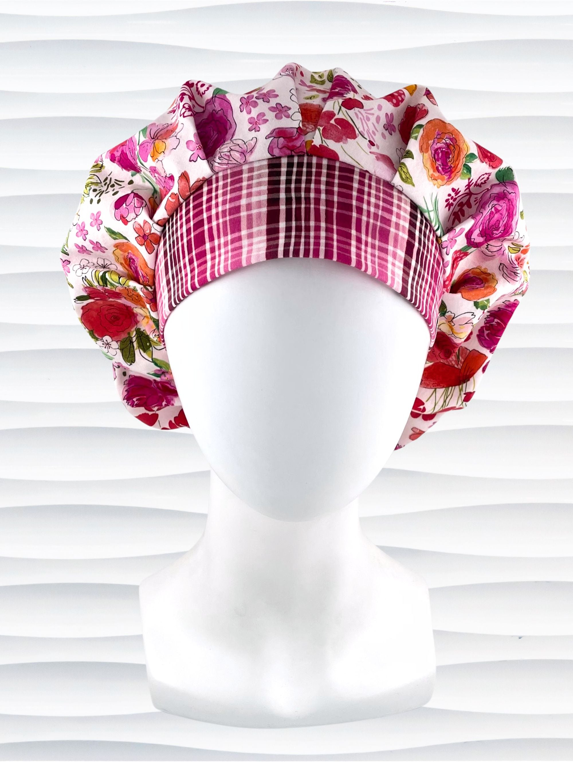 Bouffant style surgical scrub cap hat with pink, red, yellow, white, and orange flowers on white cotton fabric.