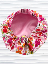 Bouffant style surgical scrub cap hat with pink, red, yellow, white, and orange flowers on white cotton fabric and satin lining.
