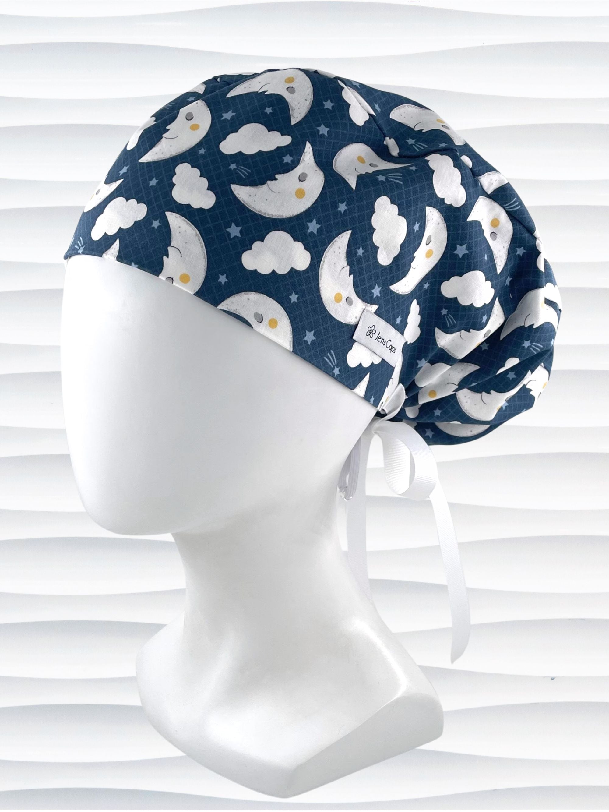 Euro Pony style surgical scrub cap hat with white moons and clouds and blue shooting stars on dark blue cotton fabric.