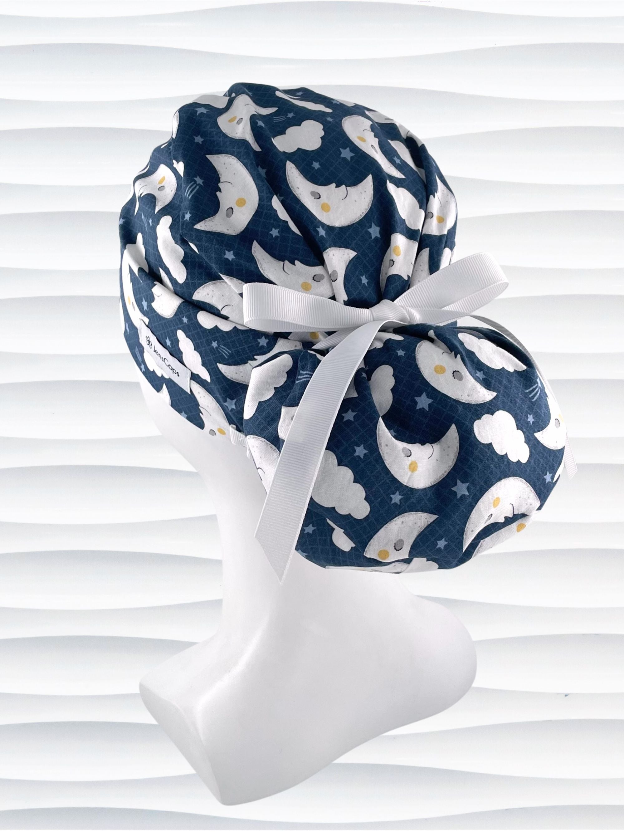 Euro Pony style surgical scrub cap hat with white moons and clouds and blue shooting stars on dark blue cotton fabric.