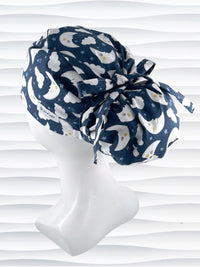 Euro Pony style surgical scrub cap hat with white moons and clouds and blue shooting stars on dark blue cotton fabric.
