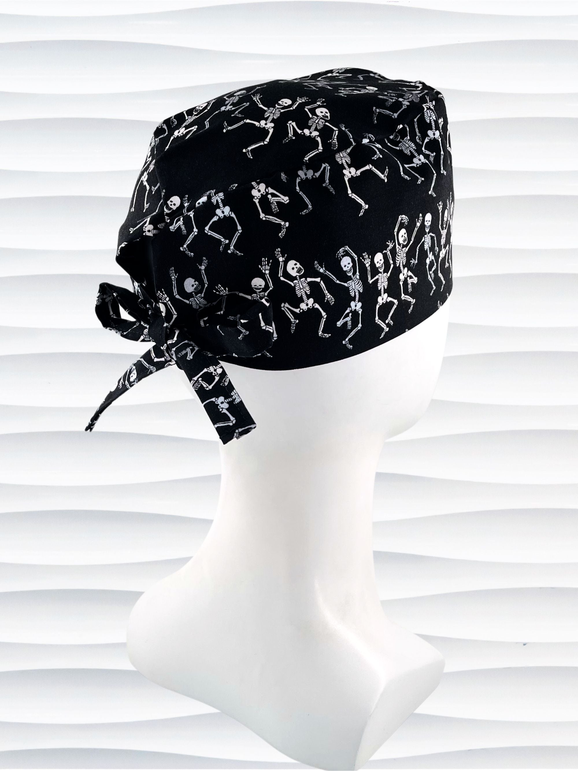 Surgeon style surgical scrub cap hat with dancing skeletons in white and gray on black cotton fabric.