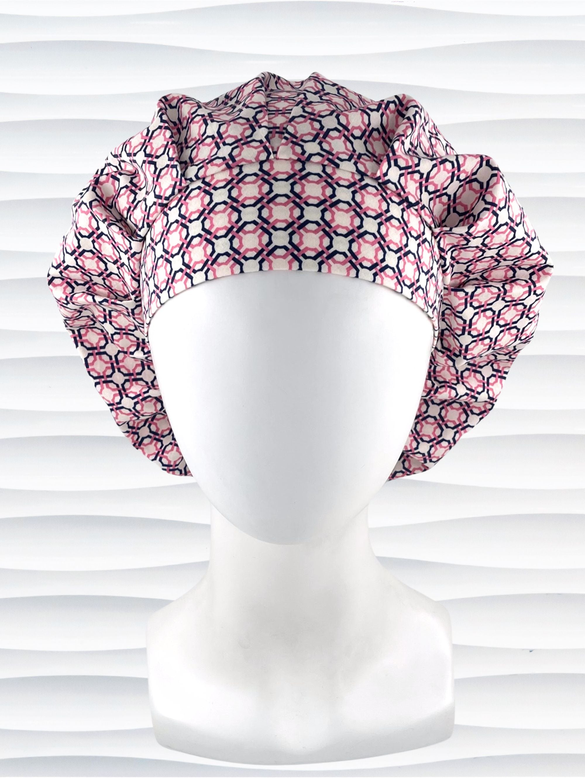 Bouffant style surgical scrub cap hat with pink and blue circles and squares in a trellis pattern on cotton fabric.