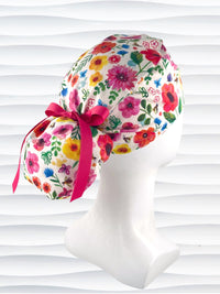 Ponytail style scrub cap hat with flowers and bees and butterflies on white premium cotton and tied with grosgrain ribbon.