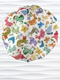 Bouffant style surgical scrub cap with cute and folksy barnyard animals, flowers, and butterflies in red, yellow, green, and blue all over white cotton fabric.