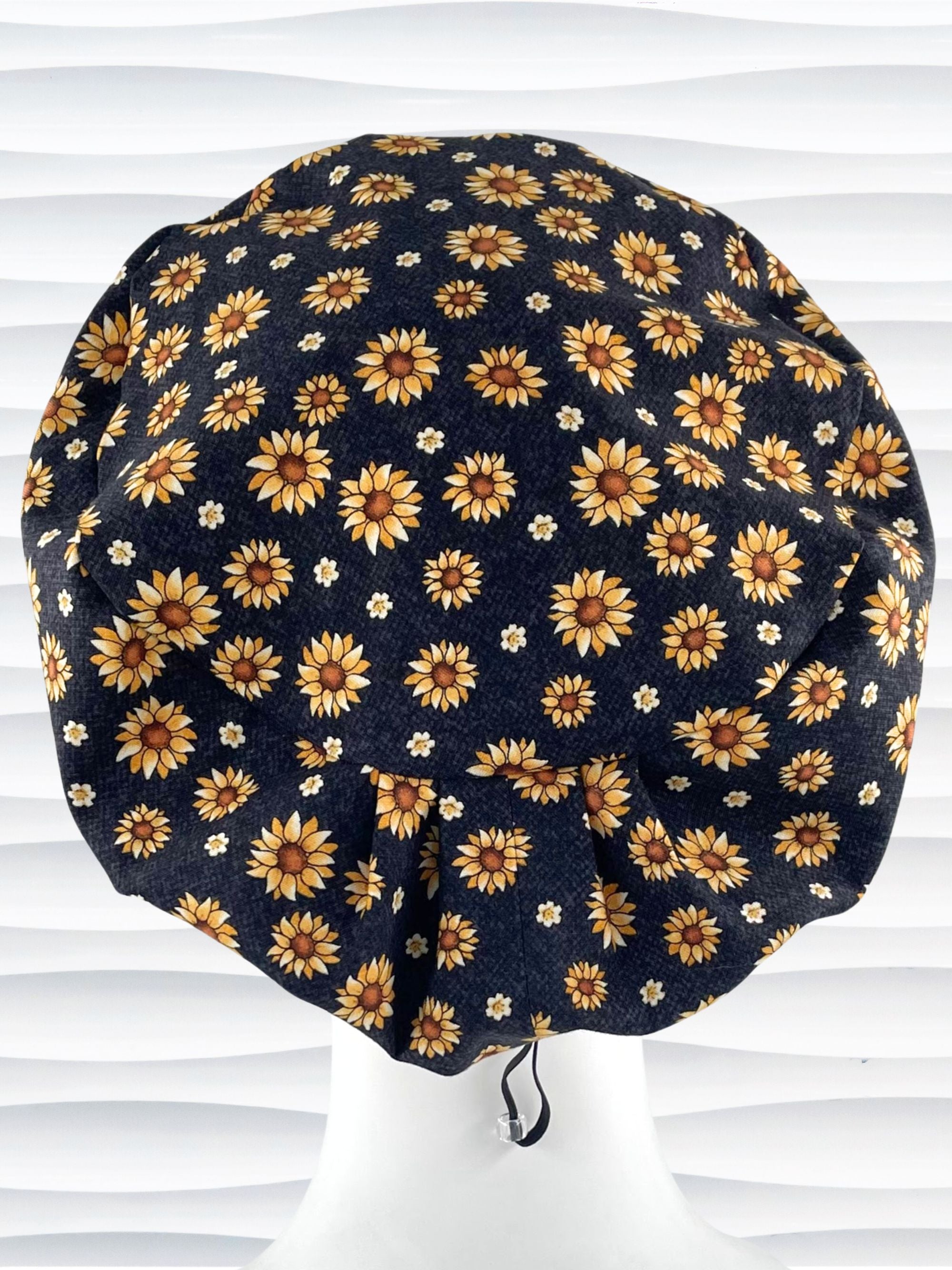 Euro Pixie style surgical scrub cap hat with sunflowers tossed all over black textured background cotton fabric.