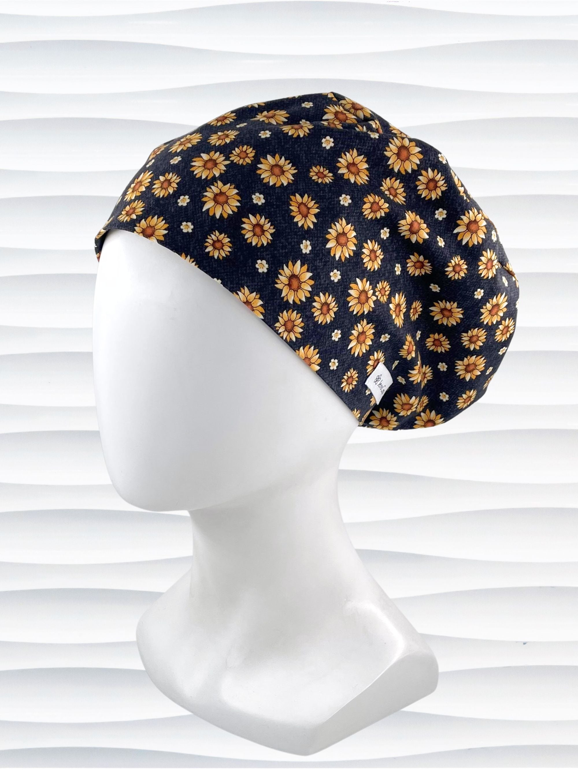 Euro Pixie style surgical scrub cap hat with sunflowers tossed all over black textured background cotton fabric.