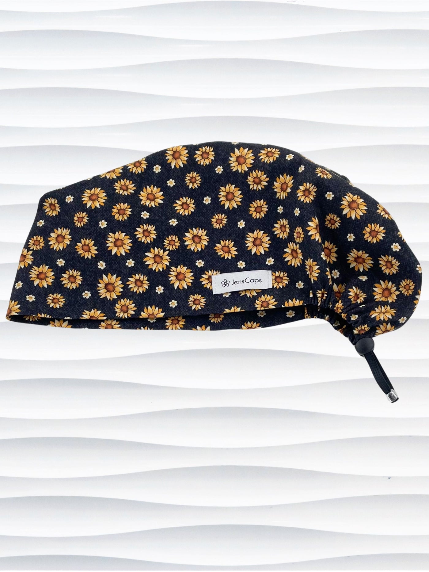 Euro Pixie style surgical scrub cap hat with sunflowers tossed all over black textured background cotton fabric.