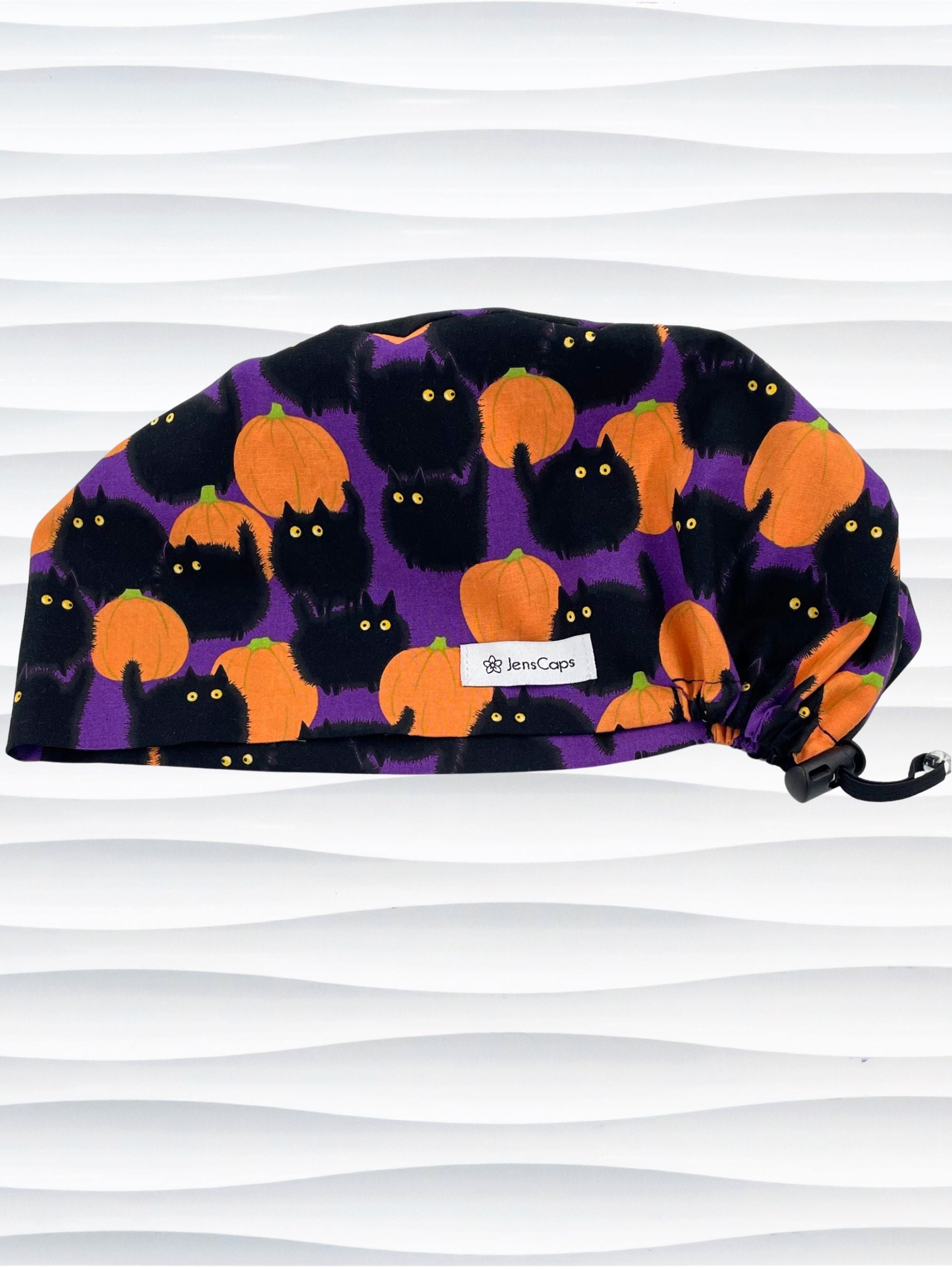 Euro Pixie style surgical scrub cap by JensCaps with black puffy cats in a pumpkin patch on purple background cotton fabric.