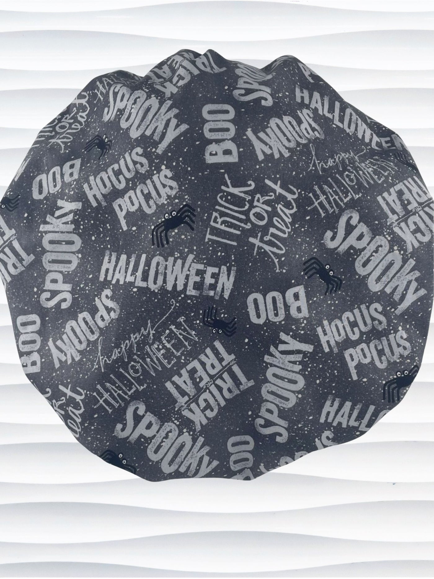 Bouffant style surgical scrub cap by JensCaps with halloween words in white and light gray and black spiders all over gray cotton fabric and displayed on a mannequin head.