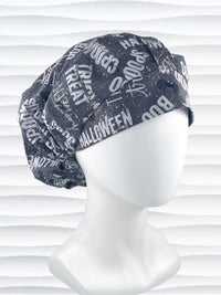 Bouffant style surgical scrub cap by JensCaps with halloween words in white and light gray and black spiders all over gray cotton fabric and displayed on a mannequin head.