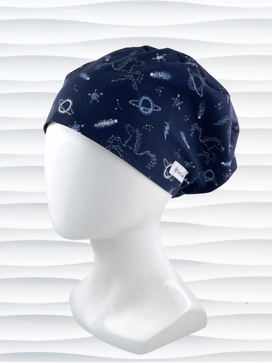 Euro Pixie style surgical scrub cap hat with shooting stars, planets, constellations, and Pegasus in white and light blue on a dark blue cotton fabric.