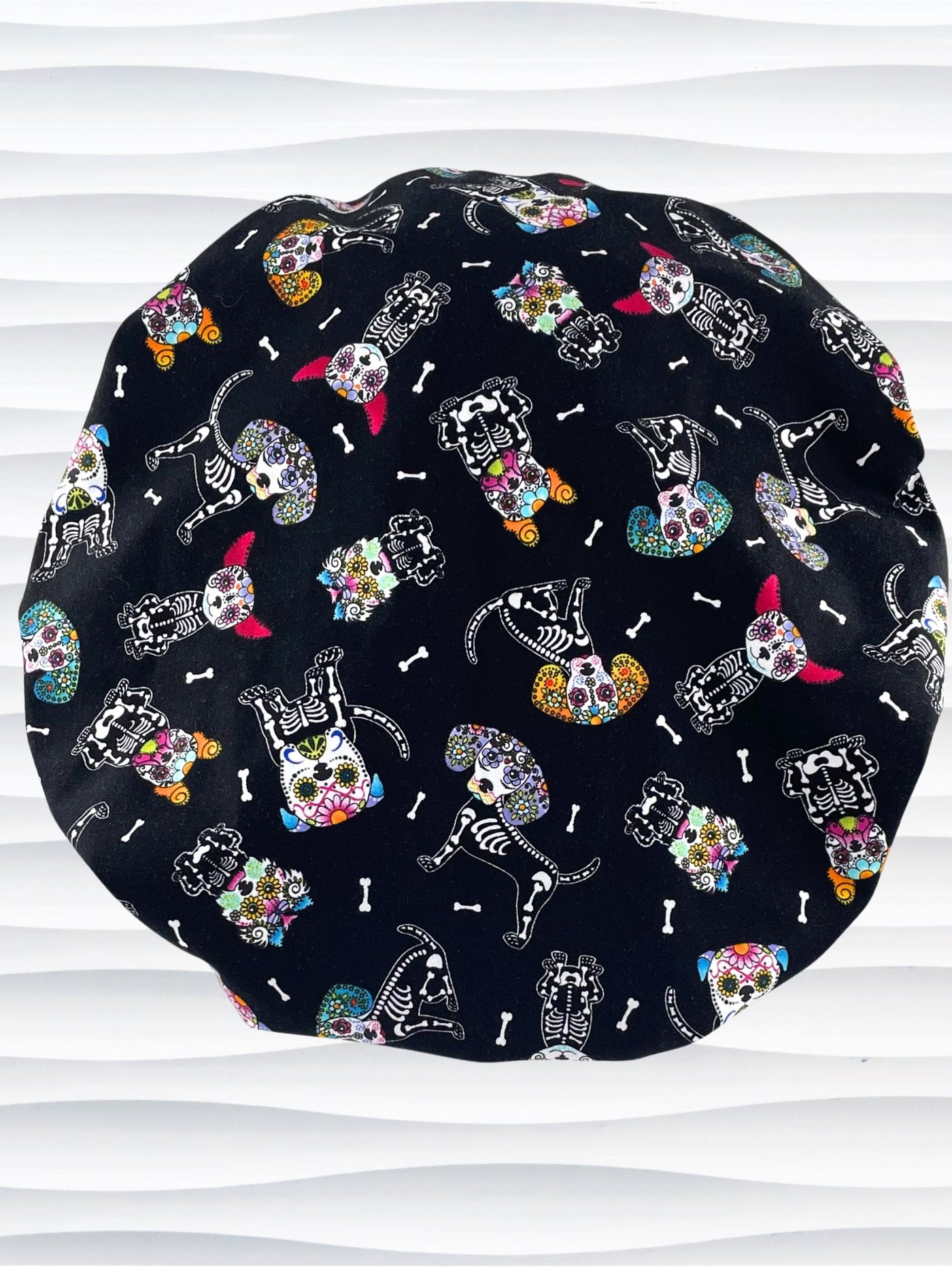 Bouffant style surgical scrub cap hat with sugar skull dogs in bright colors on black cotton fabric.