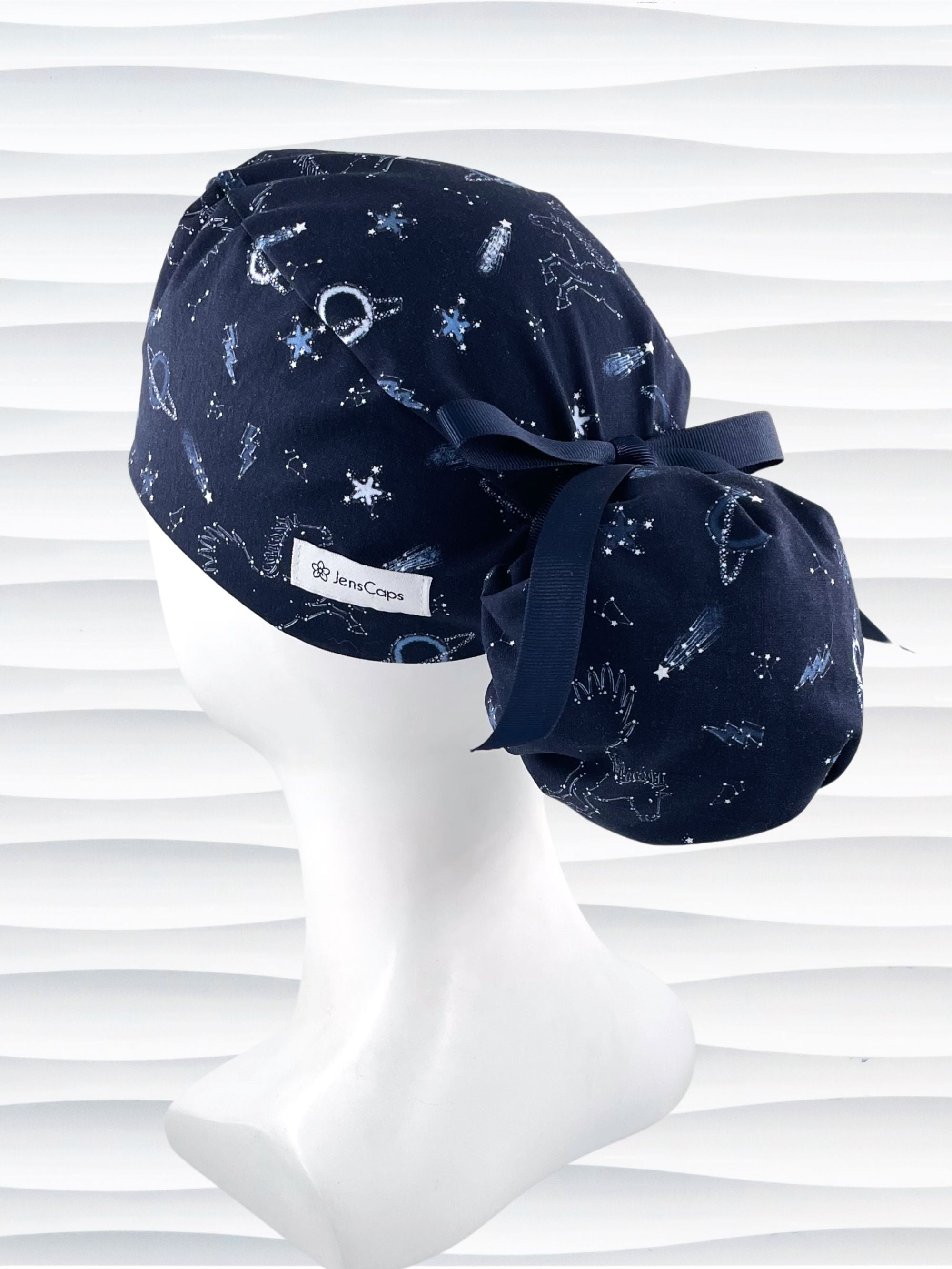 Ponytail style surgical scrub cap hat with stars, planets, and pegasus all over this dark blue cotton fabric.