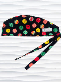 Mens surgeon style surgical scrub cap hat with christmas ornaments with smiling faces or stripes in red, green, and yellow on black cotton fabric.