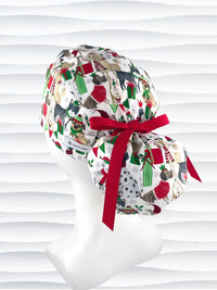 Ponytail style surgical scrub cap hat with dogs in scarves and santa hats in red, green, and white next to snowflakes and christmas presents on white cotton fabric.