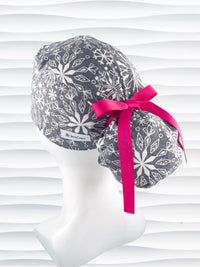 Ponytail style surgical scrub cap hat with white snowflakes all over a light gray cotton fabric.