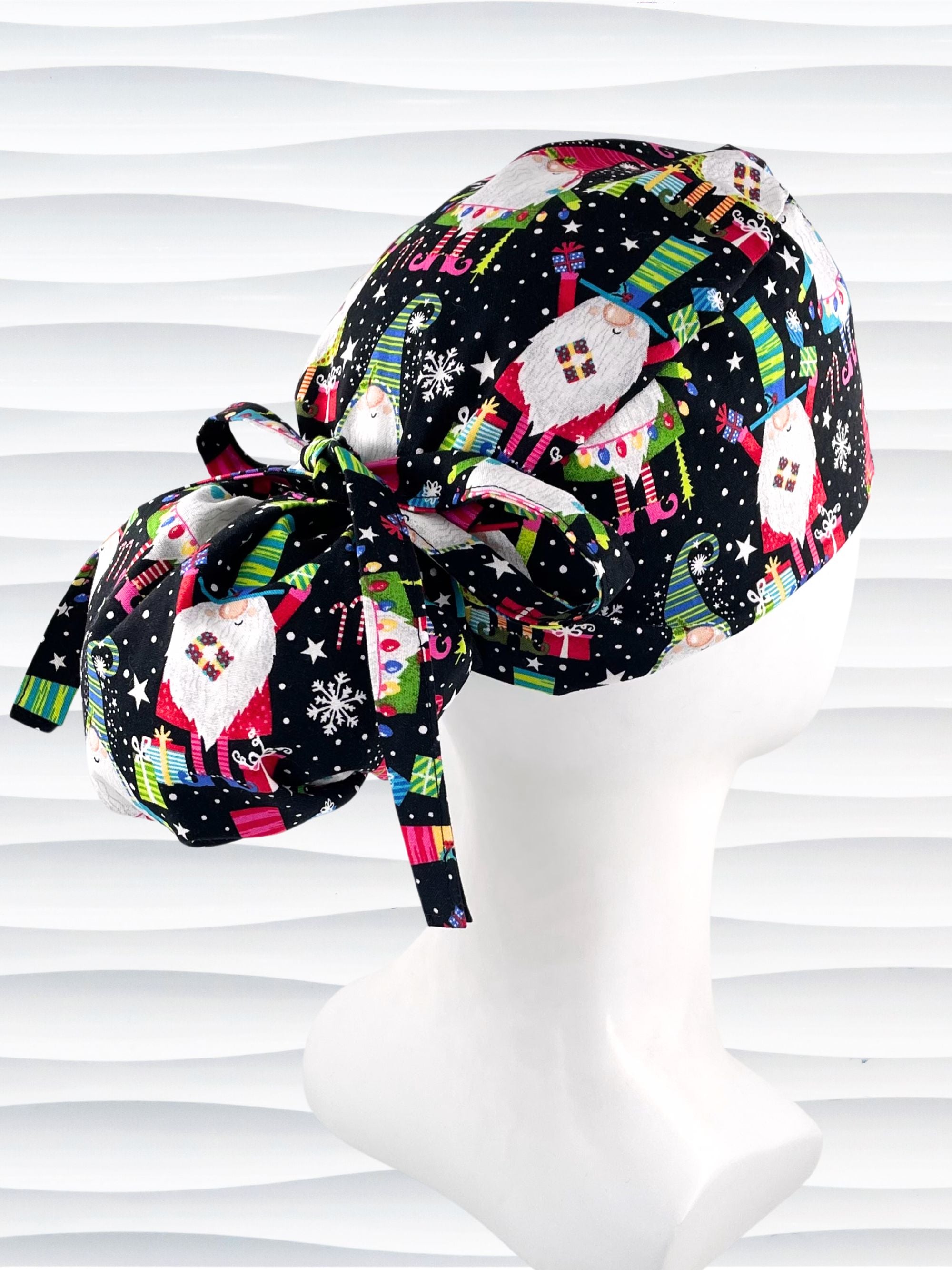 Ponytail style surgical scrub cap hat with christmas gnomes, stars, confetti, and gifts in bright colors on black cotton fabric.