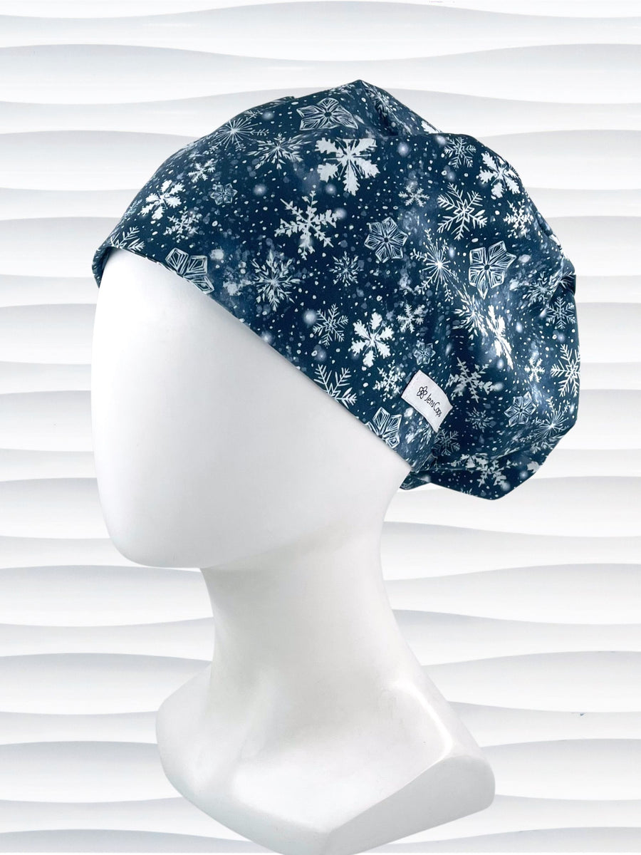 Euro Pixie style surgical scrub cap hat with white snowflakes all over blue cotton fabric.