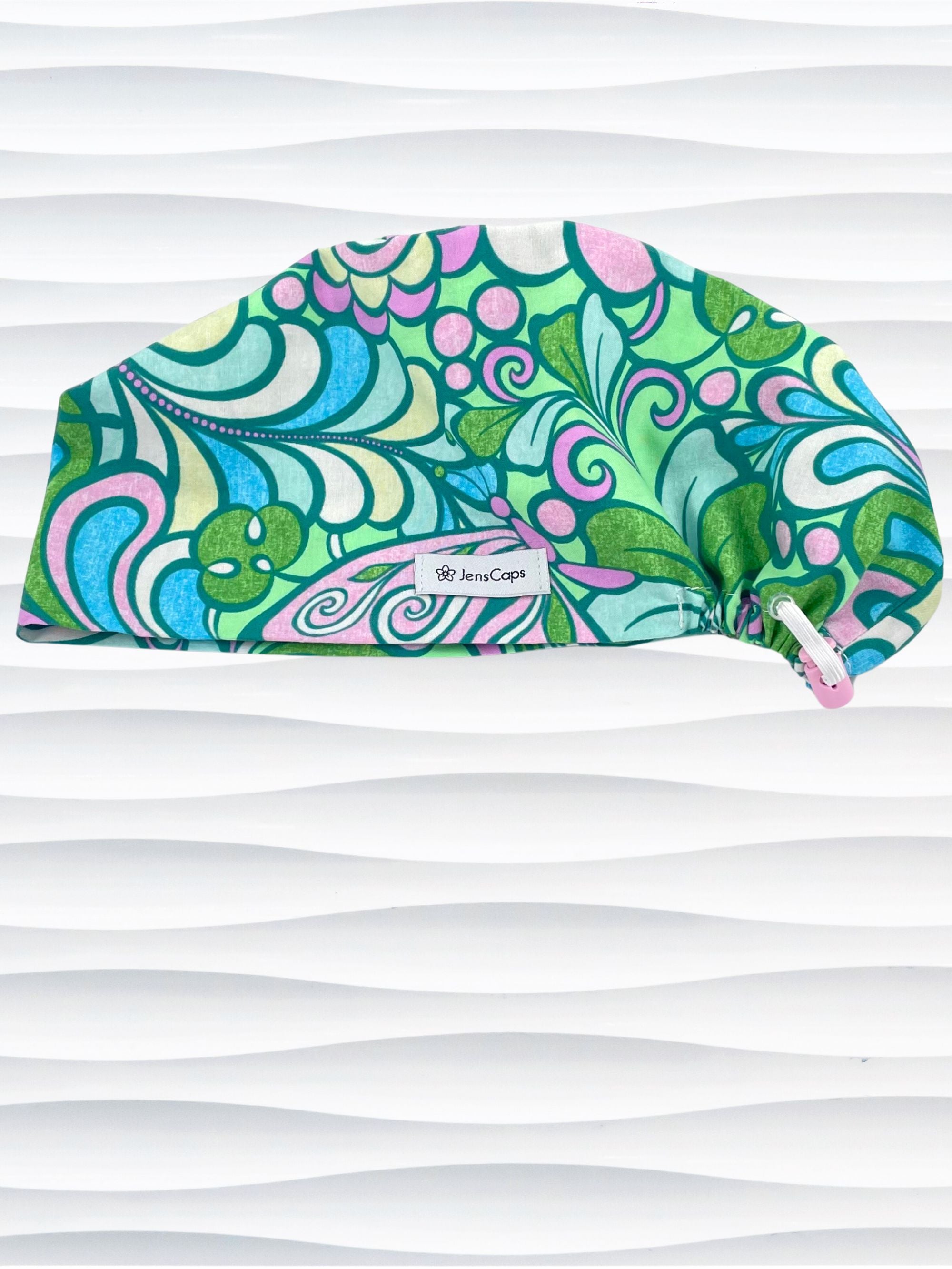 Euro Pixie style surgical scrub cap with a large and modern abstract floral print with swirls and butterflies in pinks, greens, and blues on cotton fabric.