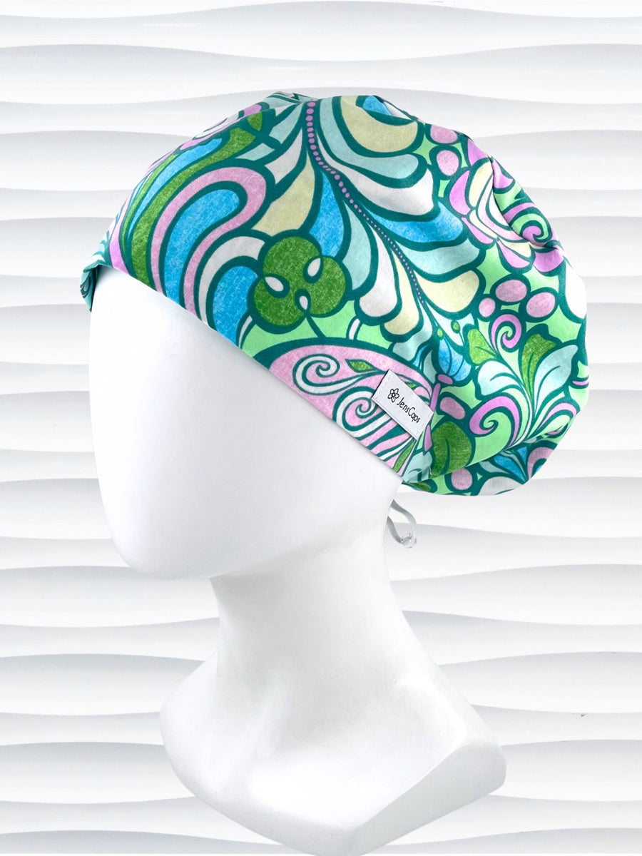 Euro Pixie style surgical scrub cap with a large and modern abstract floral print with swirls and butterflies in pinks, greens, and blues on cotton fabric.