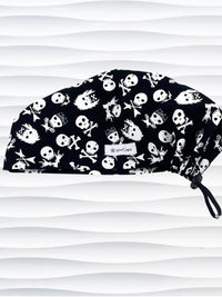 Euro Pixie style surgical scrub cap with white skulls, crossbones, and heavy metal hair all over this black cotton fabric.