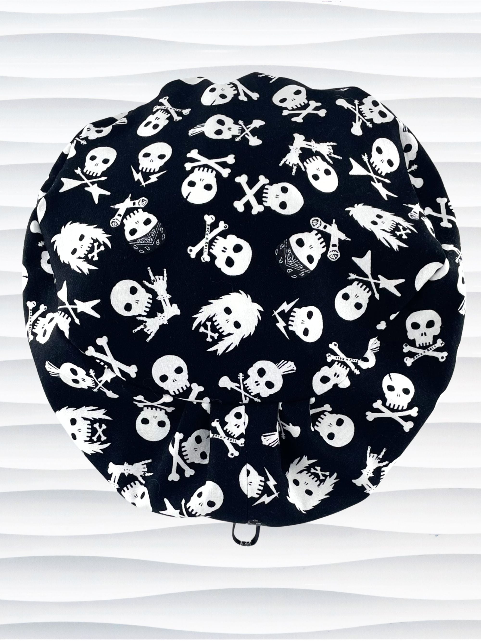 Euro Pixie style surgical scrub cap with white skulls, crossbones, and heavy metal hair all over this black cotton fabric.