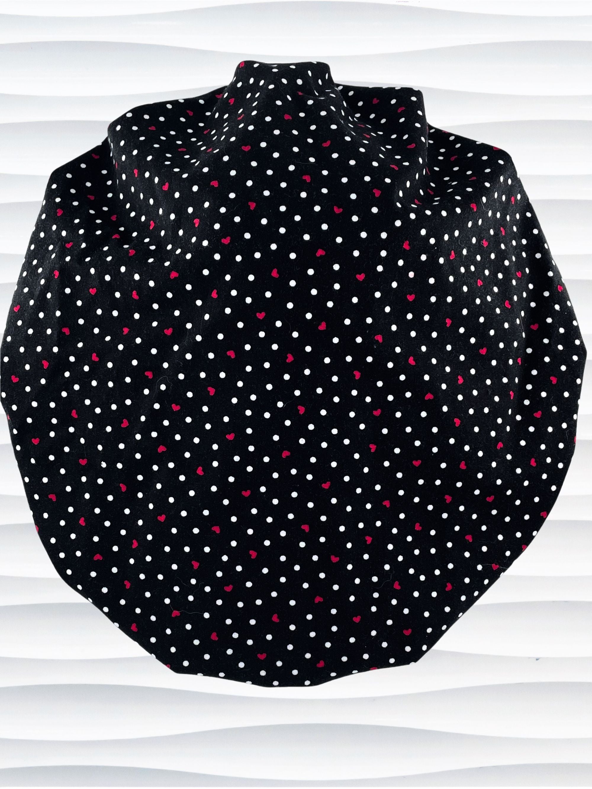 Bouffant style surgical scrub cap by JensCaps with small red hearts and white dots all over this black cotton fabric and displayed on a white mannequin head.