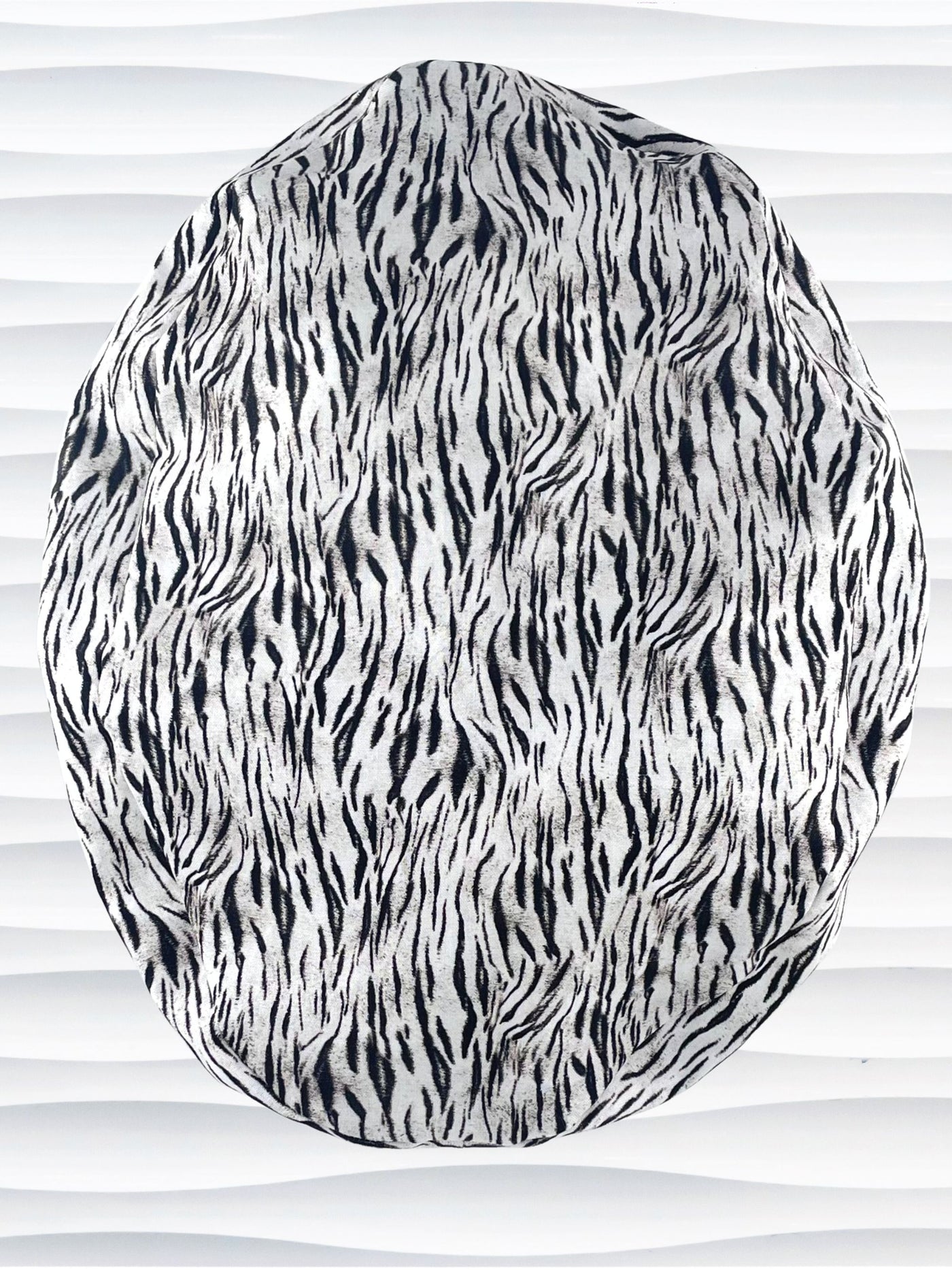 Euro style ponytail surgical scrub cap by JensCaps with a black and white zebra or snow tiger animal print on cotton fabric, finished with a grosgrain ribbon tie., and displayed on a white mannequin head.