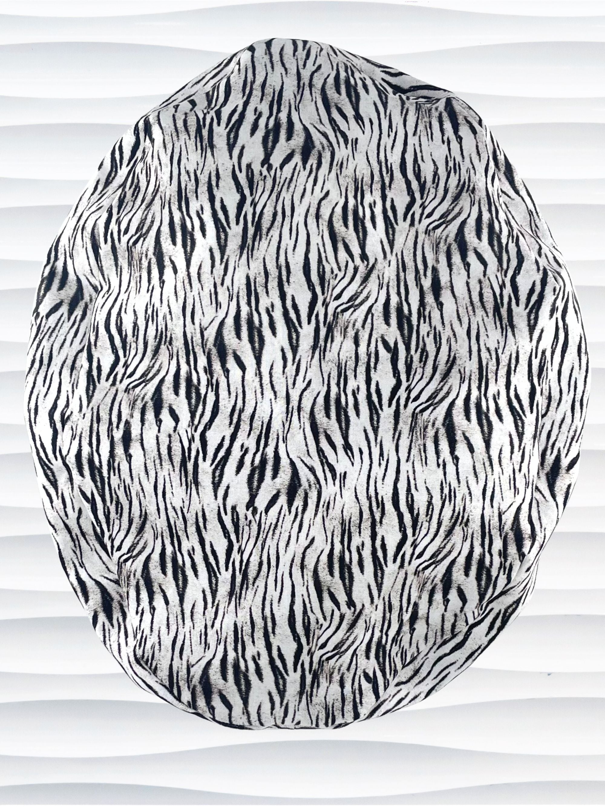 Euro style ponytail surgical scrub cap by JensCaps with a black and white zebra or snow tiger animal print on cotton fabric, finished with a grosgrain ribbon tie., and displayed on a white mannequin head.