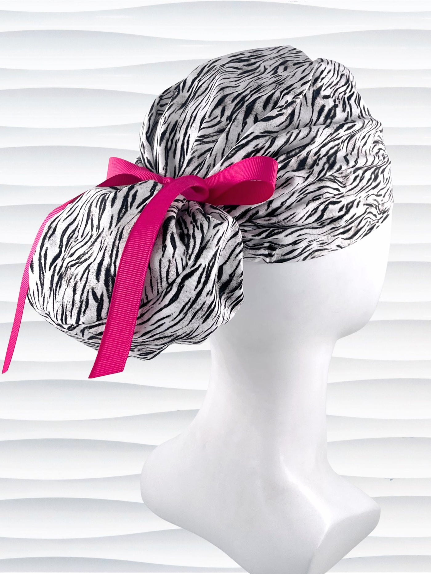 Euro style ponytail surgical scrub cap by JensCaps with a black and white zebra or snow tiger animal print on cotton fabric, finished with a grosgrain ribbon tie., and displayed on a white mannequin head.