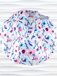 Bouffant style surgical scrub cap with watercolor looking pink and blue flowers and stems on white cotton fabric.