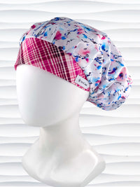 Bouffant style surgical scrub cap with watercolor looking pink and blue flowers and stems on white cotton fabric.